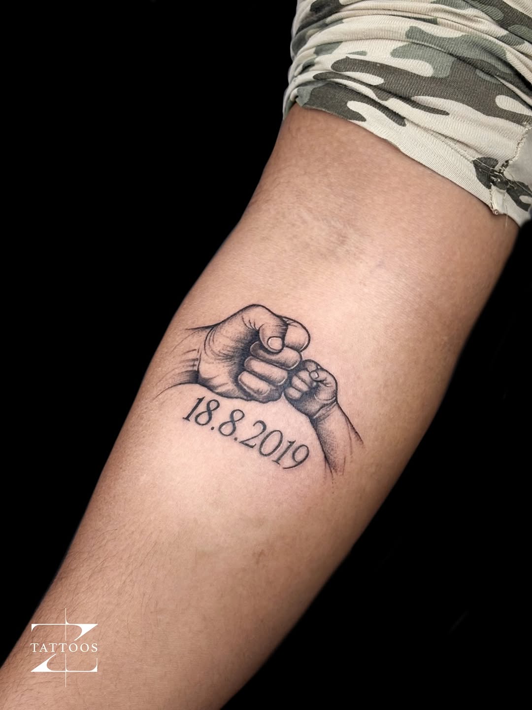 Realistic parent-and-child fist-bump memorial tattoo with the date 18.8.2019.